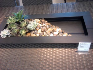 A simple metal planter with some stones and succulent plants arranged in it to look carefree.